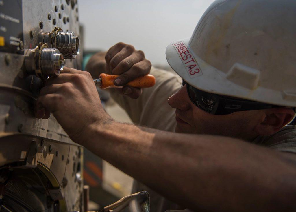 Técnico com chave de fenda ajustando componente elétrico em painel